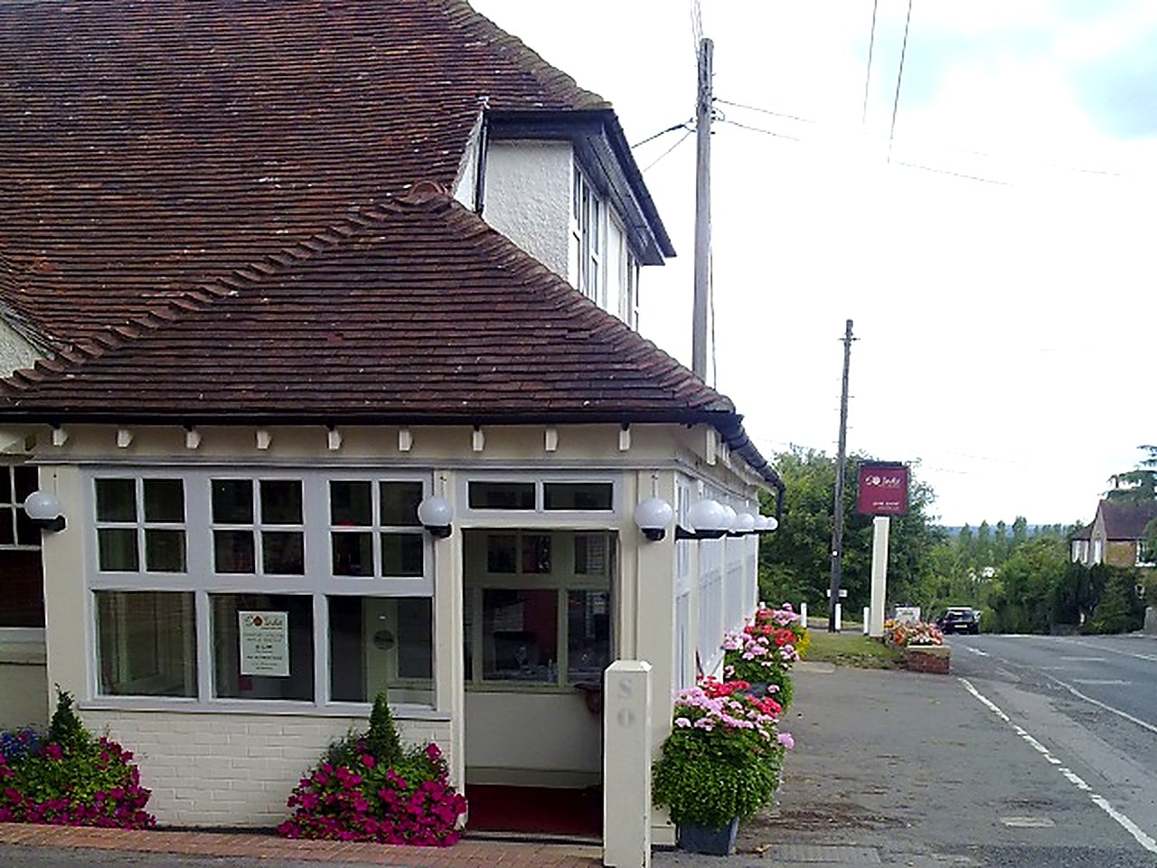 The entrance to So India, with white window frames and flower beds either side of the door
